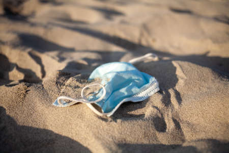 Pollution by disposable medical mask on beach by sea due coronavirus pandemic.の写真素材