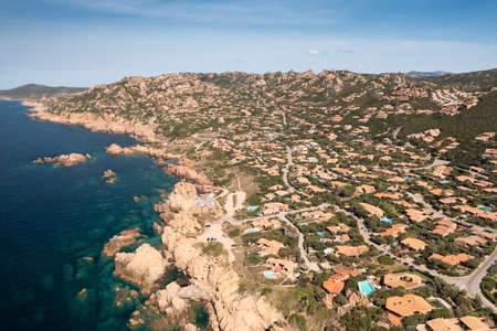 Aerial view of a stone shoreline and turquoise sea water illuminated by the sun.の写真素材