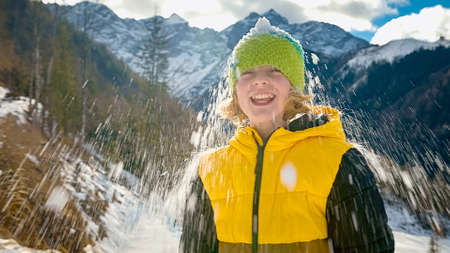 Smiling Caucasian boy having fun and playing with snow in the Alpine foothill.の写真素材