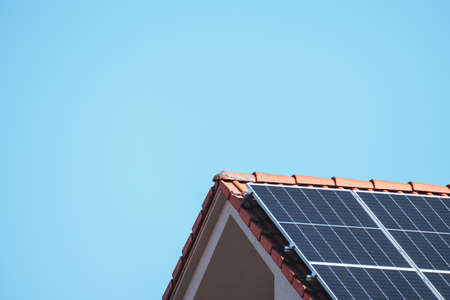 Solar photovoltaic panels on a house roof for renewable energy with blue skyの写真素材