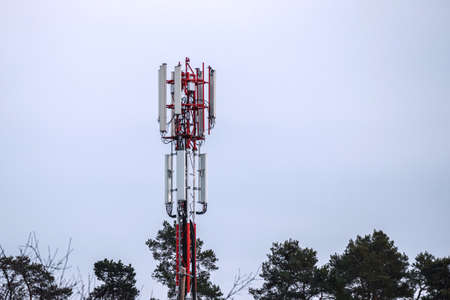 Mobile phone and internet cell tower over against sky. 5G wireless radiation antennas.の写真素材