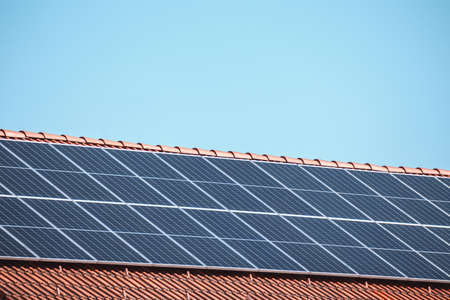 Solar photovoltaic panels on a house roof for renewable energy with blue sky