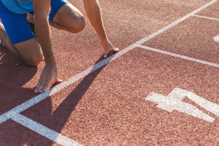 Caucasian male arms and hands on the running track starting line, ready, set and go sprint position