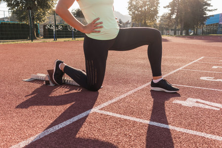 Young woman training for run race start on a stadium track outsideの写真素材
