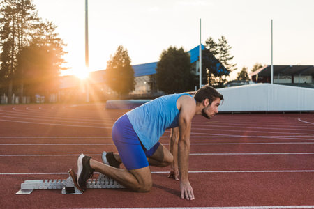 Young man training for run race start on a stadium track outsideの写真素材