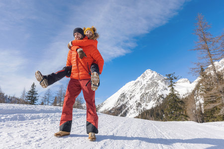 Man carries his girlfriend on his back in snowy mountain areaの写真素材