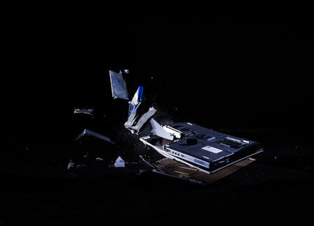 Human hands throwing a laptop falling on the hard floor and smashing into pieces scattered in space, locked down shot. Modern lifestyle, stress, and anxiety concepts.の写真素材