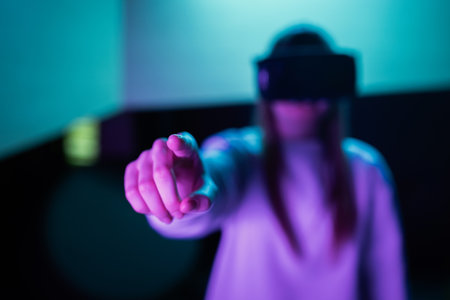 Girl in a virtual reality headset standing in front of a touch screen display making hand gestures in the air. Hand tracking concept.の写真素材