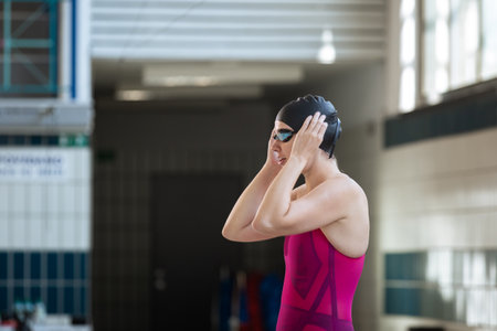 Sportswoman, a professional swimmer at the start of the swimming race, beginning drive from the block, flighting and entering into the pool waterの写真素材