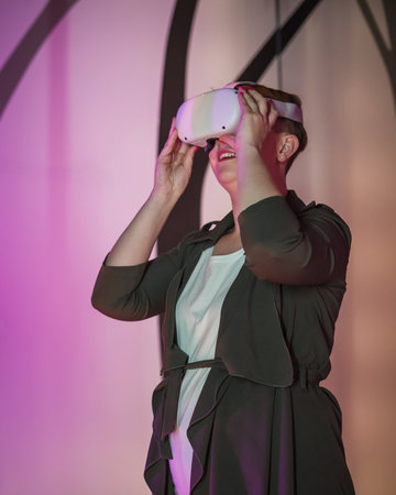 Smiling and delighted young woman enjoying VR experience, using virtual reality glasses in the natural history museum playroom.の写真素材