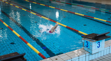 Sportswoman, a professional swimmer at the start of the swimming race, beginning drive from the block, flighting and entering into the pool waterの写真素材