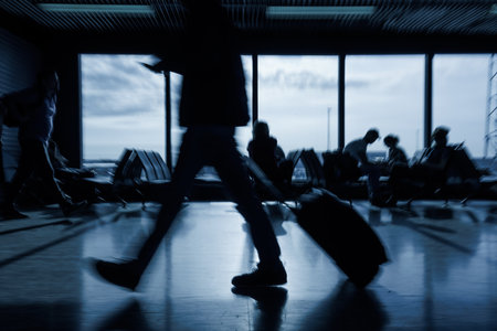 Passenger with luggage walking along an empty airport departure lounge, handheld motion blur shot. Traveling lifestyle concept.の写真素材