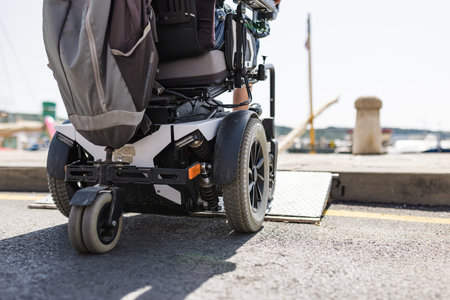 Male tourist on wheelchair crossing over the threshold ramp on the seaside promenade. Disability and...