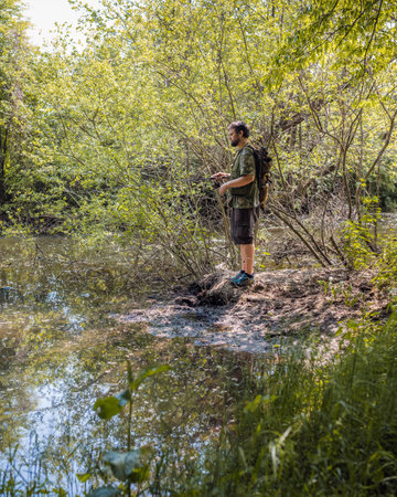 Recreational fisherman at river bank trying to catch a fish. Angler lifestyle concept.