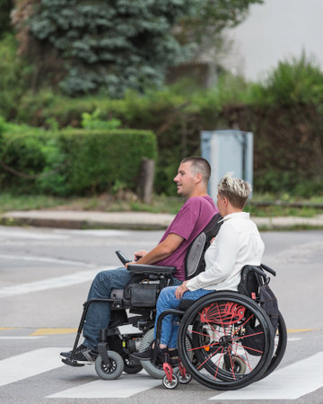 Two friends a woman and a man, wheelchair users spending time outdoors. Life with disability, support, and friendship concepts.の写真素材