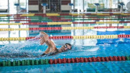 Professional female swimmer swimming the front crawl stroke. Freestyle competition concept.