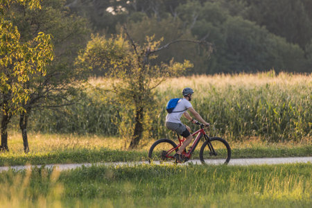 Man biking electric mountain bike along the trail in a fantastic rural landscape at sunsetの写真素材