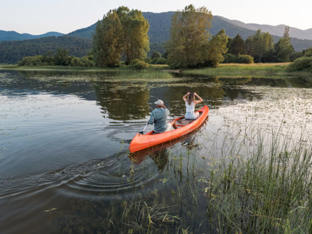 Couple spending a hot summer afternoon on the lake, gently paddling a canoe on calm water. Canoeing and healthy lifestyle concepts.の写真素材