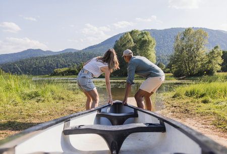 Cheerful couple on a summer lake vacation, going on a canoe ride. Romantic weekend getaway concept.の写真素材
