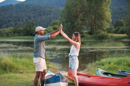 Happy couple enjoying a summer canoe ride on the lake, relaxing surrounded by beautiful green nature. Canoeing trip concepts.の写真素材