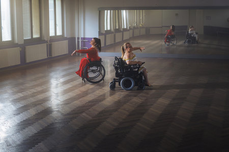 Two women with a disability, wheelchair dancers practicing dance performance in a ballroom. Dancesport and accessibility concept.の写真素材