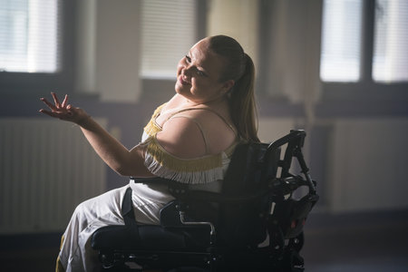Young smiling woman with a disability enjoying making elegant graceful moves while dancing in a...