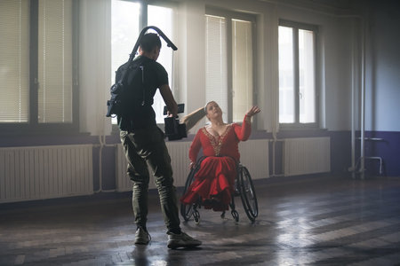 Female para dancer performing dance choreography on wheelchair with cameraman filming.