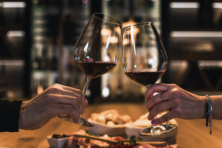 Smiling couple dining in a wine cellar room, enjoying fine white wine and delicious foodの写真素材