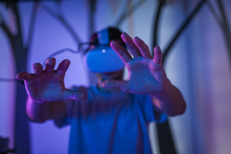 Young man with a virtual reality headset enjoying a multimedia experience in the dark VR room, a simulation of being in the forest.の写真素材