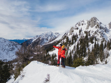Mountaineer couple enjoy the amazing snowy landscape from the top of a mountain, aerial viewの写真素材