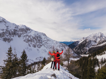 Mountaineer couple enjoy the amazing snowy landscape from the top of a mountain, aerial viewの写真素材