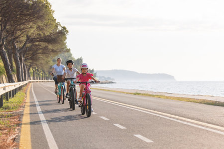 Mother with son and little daughter relaxed cycling on a coastal route, with a view out over the sea