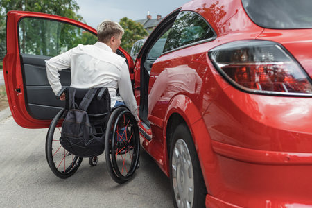 Businesswoman, a driver with a disability getting into a red car. Transport, driving, and physical impairment concepts.の写真素材