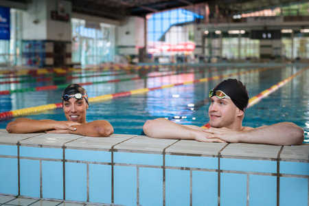 Portrait of two young woman and man athlete swimmer in pool with gogglesの写真素材