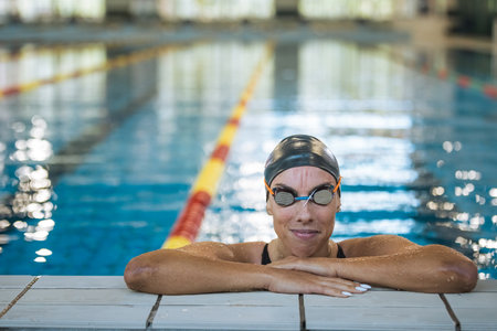 Portrait of a woman, a professional swimmer in black one-piece swimwear and a black cap with gogglesの写真素材