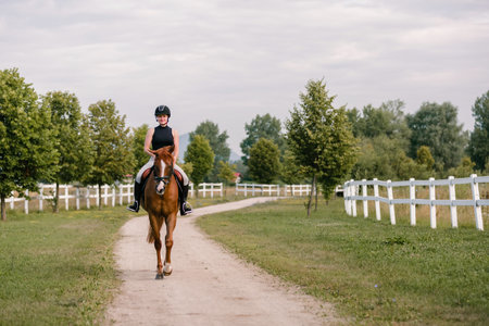 Young woman and her beautiful red horse during calm trail ride. Ecotourism and animal care concepts.の写真素材