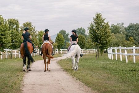 Horsewomen riding beautiful horses along the trail at the equestrian center on a bright summer day. Horse gait walks concept.の写真素材