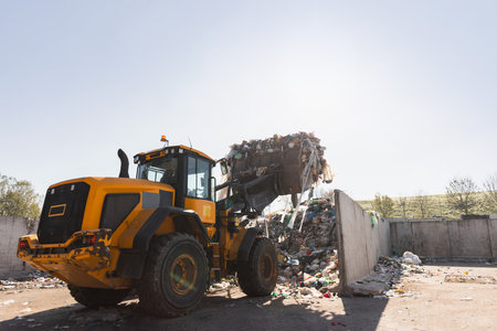 Heavy construction machine, front end loader moving along recycling center area, close up view. Waste management industry concept.の写真素材