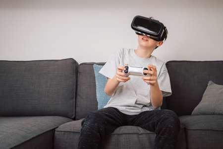 Boy having fun playing simulation games, using virtual reality headset and controller. Children and...