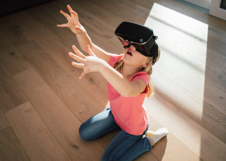 Caucasian female kid in a virtual reality headset sitting on the living room floor, looking around excited on the virtual worldの写真素材