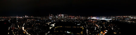 London business district panorama, Canary Wharf cityscape at night, glittering residential towers, skyscrapers, and modern buildings rising on the skyline, aerial view.の写真素材