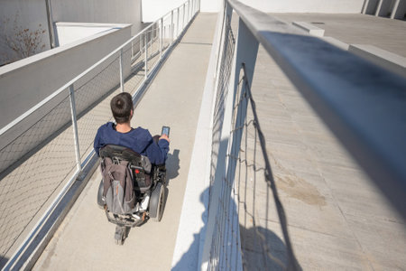 Man in a wheelchair use an accessible ramp.の写真素材