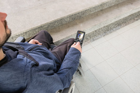 Man with disability on wheelchair stopped in front of staircase, raising awareness of architectural...