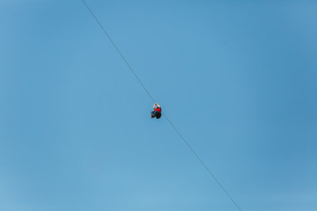 Man having fun on a zip line at summer against blue skyの写真素材