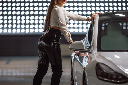 Attractive young woman charging a luxury electric car at an electric vehicle charging station in a public garageの写真素材