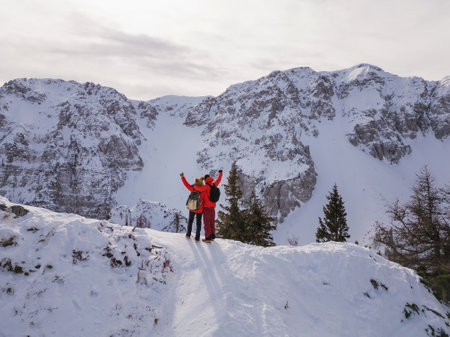 Mountaineer couple enjoy the amazing snowy landscape from the top of a mountain, aerial viewの写真素材