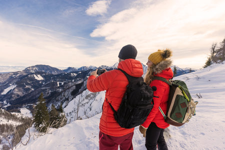 Mountaineers take photo of snowy landscape in the mountains with their dog in winterの写真素材