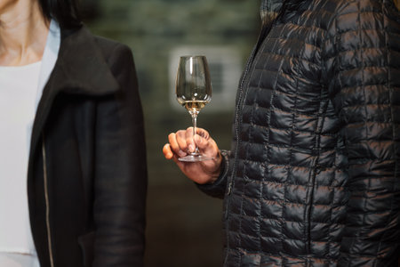Caucasian couple standing near a large wooden barrel in a wine cellar and tasting a quality white wineの写真素材