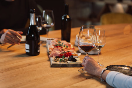 People drinking wine and eating cold cut meat in a wine cellar.
