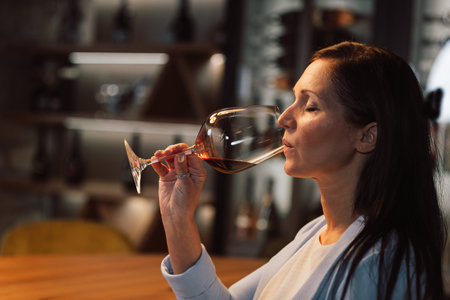 Woman tasting wine at the wine cellar with barrels in backgroundの写真素材